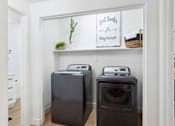 Thumbnail 11 of 51 - Two black front load washing machines in a laundry room. at The Laurel Apartments, Chandler, 85286  