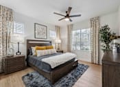 Thumbnail 7 of 51 - A bedroom with a bed, nightstands, and a ceiling fan. at The Laurel Apartments, Chandler, AZ  
