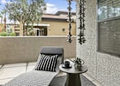 Thumbnail 16 of 51 - A grey chair with a black cushion is on a patio with a table in front of a building. at The Laurel Apartments, Arizona  