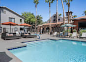 Thumbnail 6 of 40 - A pool surrounded by palm trees and lounge chairs. at Lazo Apartment Homes, Chandler  