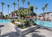 Thumbnail 27 of 40 - A pool surrounded by palm trees and plants. at Lazo Apartment Homes, Chandler, 85225  