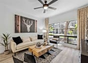 Thumbnail 2 of 40 - A living room with a white couch, a wooden coffee table, and a deer head picture on the wall. at Lazo Apartment Homes, Chandler Arizona  