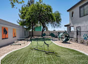 Thumbnail 7 of 40 - A playground with a swing set and a tree in the middle of a grassy area. at Lazo Apartment Homes, Chandler Arizona  
