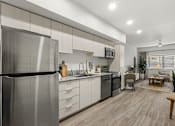 Thumbnail 13 of 26 - Modern kitchen with stainless steel appliances and granite countertops at Lucero Apartments, Phoenix, AZ