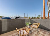 Thumbnail 24 of 26 - Private patio with wicker chairs and table at Lucero Apartments, Phoenix