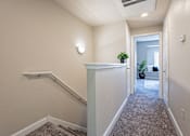 Thumbnail 14 of 42 - A hallway with a carpeted floor and a staircase on the left side.at Palazzo Townhomes, Phoenix, AZ 85008  