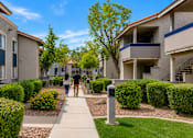 Thumbnail 3 of 20 - Two people walking down a sidewalk between two buildings.