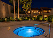 Thumbnail 9 of 20 - A pool lit up at night with a house in the background.