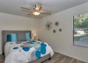 Thumbnail 8 of 34 - A bedroom with a bed, pillows, a ceiling fan, and a window with blinds at Reflections at Red Mountain Apartments, Arizona