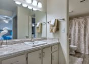 Thumbnail 9 of 34 - A bathroom with a marble countertop and a shower with a curtain. at Reflections at Red Mountain Apartments, Mesa, AZ, 85213
