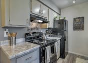 Thumbnail 6 of 34 - A kitchen with a black refrigerator and a white counter top at Reflections at Red Mountain Apartments, Mesa, Arizona