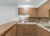 Thumbnail 3 of 26 - A kitchen with wooden cabinets and a white stove top oven at The Phoenix Apartments on 6th Avenue, Phoenix