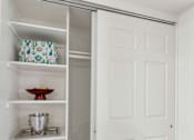 Thumbnail 12 of 36 - A white pantry with an open door and a bowl on the shelf at Urban WalkApartments on 6th Avenue, Phoenix, AZ