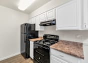 Thumbnail 14 of 36 - A black fridge and stove in a kitchen with white cabinets at Urban WalkApartments on 6th Avenue, Arizona 85016