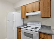 Thumbnail 21 of 36 - A white refrigerator and stove in a kitchen with wooden cabinets at Urban WalkApartments on 6th Avenue, Arizona