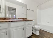 Thumbnail 25 of 36 - A white bathroom with a marble countertop and wooden flooring at Urban WalkApartments on 6th Avenue, Arizona 85016