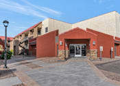 Thumbnail 30 of 36 - A building with a red and beige exterior and a stone pillar in front at Urban WalkApartments on 6th Avenue, Arizona
