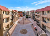 Thumbnail 35 of 36 - A courtyard surrounded by apartment buildings with a brick walkway and a small tree at Urban WalkApartments on 6th Avenue, Phoenix, Arizona