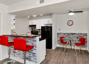 Thumbnail 4 of 36 - A kitchen with a bar area and red chairs at Urban WalkApartments on 6th Avenue, Phoenix