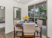 Thumbnail 11 of 29 - A dining room with a table set for two and a view of a residential area outside the window.