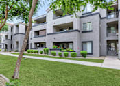 Thumbnail 8 of 29 - Apartment building with greenery in front.