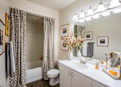 Thumbnail 14 of 25 - A bathroom with a white sink, toilet, and a mirror.