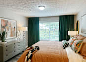 Thumbnail 15 of 28 - A bedroom with a bed, dresser, and window with green curtains.