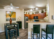 Thumbnail 14 of 27 - a kitchen with a bar and stools next to a living room with a refrigerator