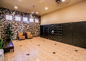 Thumbnail 24 of 27 - a large locker room with black lockers and chairs and a plant