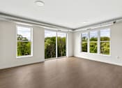 Thumbnail 6 of 6 - A room with wooden floors and large windows overlooking a green landscape.