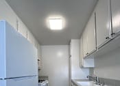 Thumbnail 3 of 7 - A kitchen with white appliances and cabinets.
