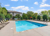 Thumbnail 7 of 21 - a swimming pool with chairs and a building in the background