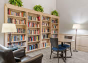 Thumbnail 17 of 21 - a library with a table and chairs and shelves of books