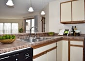 Thumbnail 4 of 32 - A kitchen with a sink, a window, and a bowl of fruit on the counter.
