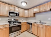 Thumbnail 1 of 25 - A kitchen with wooden cabinets and stainless steel appliances.