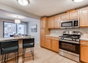 Thumbnail 2 of 25 - A kitchen with wooden cabinets and a stainless steel oven.