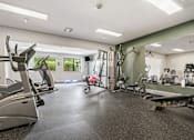 Thumbnail 19 of 21 - A gym with treadmills, exercise bikes, and other equipment.