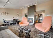 Thumbnail 18 of 21 - A living room with a fireplace and two orange chairs.