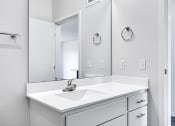 Thumbnail 23 of 44 - bathroom sink and mirror with white countertop, walls, and shelves