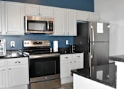 Thumbnail 5 of 16 - A kitchen with white cabinets and a black counter.