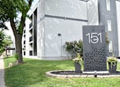 Thumbnail 4 of 20 - A grey sign with the number 151 on it in front of a building.