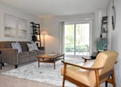 Thumbnail 1 of 27 - A living room with a brown couch, a wooden coffee table, and a tan leather chair.