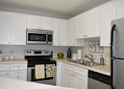 Thumbnail 2 of 27 - A kitchen with white cabinets and appliances.