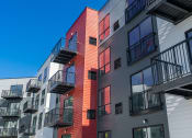 Thumbnail 27 of 44 - outside of red, gray, and white apartments with balconies