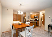 Thumbnail 7 of 32 - Kitchen and dining room with white chairs, wooden table, and a bright hanging lamp