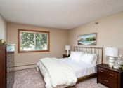 Thumbnail 12 of 32 - Bedroom with white comforter, and a lamp on the wooden nightstand