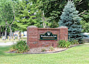 Thumbnail 27 of 29 - A sign for Washburn on the Park Luxury Apartments is displayed in front of a tree.