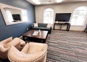 Thumbnail 6 of 13 - A living room with a couch, chairs, and a television.
