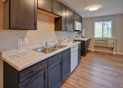 Thumbnail 1 of 11 - a kitchen with wood flooring and a large counter with a sink