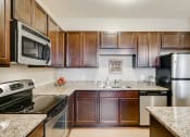 Thumbnail 1 of 25 - Community kitchen with dark wooden cabinets and silver appliances